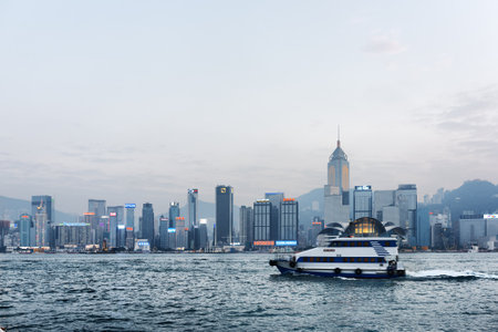 Boat crosses Victoria harbor and view of skyscrapers in business center of Hong Kong city at...