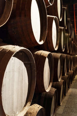 Side view of oak barrels stacked in the old cellar with aging Port wine from the vineyards Douro...