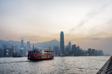 Tourist boat in Victoria harbor and view of skyscrapers in business center of Hong Kong city at sunset. Hong Kong is popular tourist destination of Asia.のeditorial素材