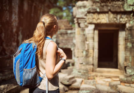 Young female tourist with blue backpack in mysterious ruins of ancient Preah Khan temple in Angkor. Siem Reap, Cambodia.の写真素材
