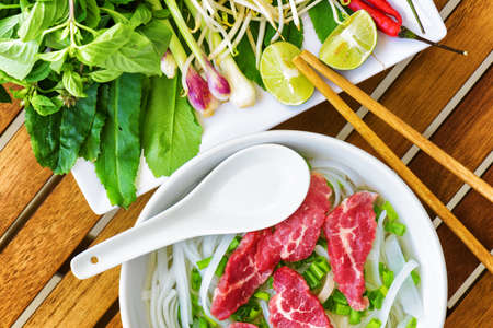Top view of the Pho Bo on wooden table of street cafe in Vietnam. The Pho Bo is a traditional...