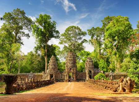 Stone Asuras on bridge leading to ancient Preah Khan temple in Angkor, Siem Reap, Cambodia. Entrance gopura on woods background. Mysterious Angkor is a popular tourist attraction.の写真素材