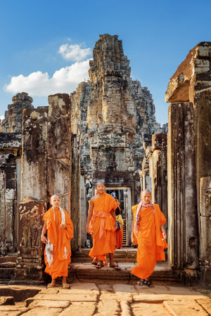 SIEM REAP, CAMBODIA - MAY 4, 2015: Young Buddhist monks coming out of ancient Bayon temple in Angkor Thom. Mysterious Angkor Thom is a popular destination of tourists and pilgrims.のeditorial素材