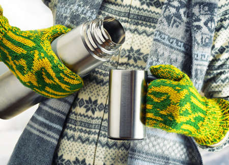 Woman is pouring a hot drink in mug from thermos.の写真素材