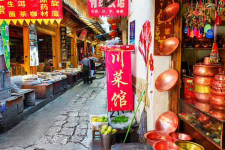 LIJIANG, YUNNAN PROVINCE, CHINA - OCTOBER 23, 2015: Traditional oriental Chinese handmade utensils and copper hot pots (steamboats) at gift shop on scenic narrow street in the Old Town of Lijiang.のeditorial素材