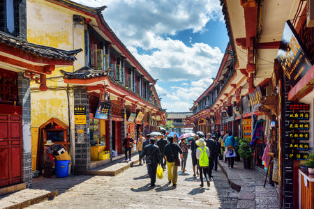 LIJIANG, YUNNAN PROVINCE, CHINA - OCTOBER 23, 2015: Scenic view of traditional oriental Chinese houses on blue sky background. Asian tourists are walking on ancient street in the Old Town of Lijiang.のeditorial素材