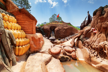 Dalat, Vietnam - March 31, 2016: Amazing canyon with clay houses and sculptures of animal and vegetables at the Dalat Star. Man-made waterfall in artificial mountain is visible on blue sky background.のeditorial素材