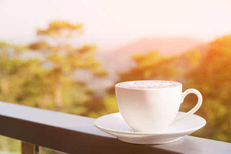 Cup of hot Cappuccino coffee on nature background. Fresh invigorating drink on terrace of cafe. Toned image.の写真素材