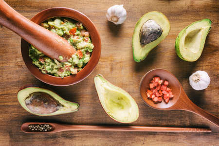 Top view of fresh homemade Guacamole in wooden mortar with pestle (molcajete). Traditional Mexican sauce from ripe avocados on wooden table. Healthy vegetarian food.の写真素材