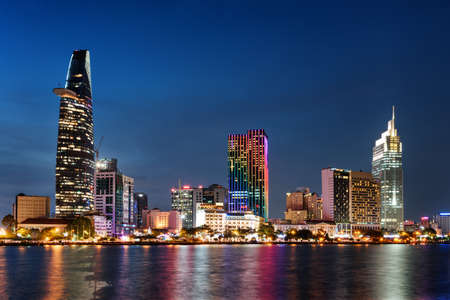 Ho Chi Minh City skyline and the Saigon River. Amazing colorful night view of skyscraper and other...