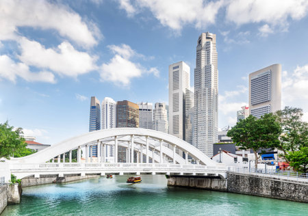 Wonderful view of scenic white bridge over the Singapore River with azure water. Skyscrapers and other modern buildings of downtown are visible on blue sky background. Amazing summer cityscape.のeditorial素材
