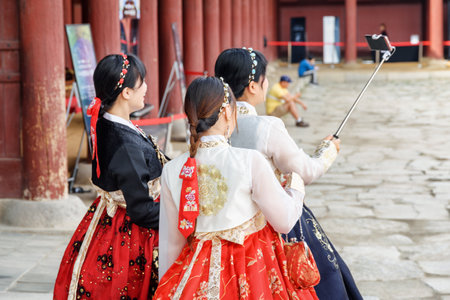 Seoul, South Korea - October 9, 2017: Pretty girls wearing Korean traditional dress Hanbok and using smartphone in Gyeongbokgung Palace. Girls taking pictures.のeditorial素材
