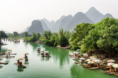 Guilin, China - September 19, 2017: Asian tourists traveling by small bamboo rafts along the Yulong River in Yangshuo County. Amazing karst mountains are visible in background. Beautiful landscape.のeditorial素材
