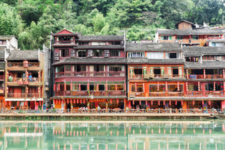 Fenghuang, China - September 22, 2017: Scenic traditional Chinese riverside buildings reflected in water of the Tuojiang River (Tuo Jiang River) in Phoenix Ancient Town (Fenghuang County).のeditorial素材
