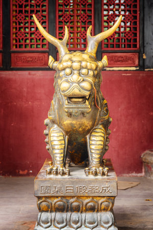 Chengdu, China - September 25, 2017: Statue of mystical Chinese guardian lion on red wall background in Wenshu Temple (Buddhist Monastery).のeditorial素材