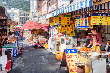 Busan, South Korea - October 7, 2017: Korean woman cooking at street cafe in Jagalchi Fish Market. Traditional street food. Jagalchi Fish Market is a popular tourist attraction of Asia.のeditorial素材