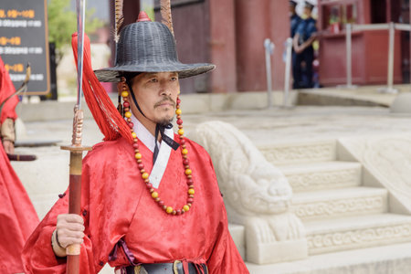 Seoul, South Korea - October 9, 2017: Ceremonial portrait of royal guard wearing red Jeonbok at courtyard of Gyeongbokgung Palace. Korean traditional military clothing.のeditorial素材