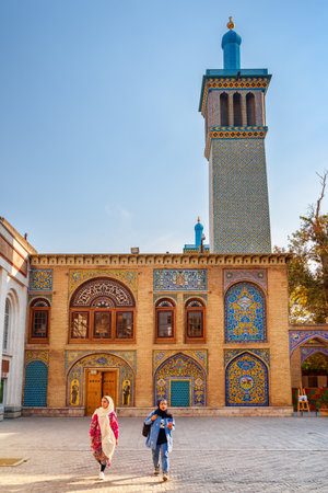 Tehran, Iran - 19 October, 2018: Young Iranian women walking along courtyard of the Golestan Palace. Colorful Persian exterior. Amazing windcatcher (badgir) is visible on blue sky background.のeditorial素材