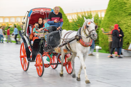 Isfahan, Iran - 24 October, 2018: Young pretty Iranian family using horse and buggy in Naqsh-e Jahan Square. The square is a popular tourist attraction and recreational gathering place among residentsのeditorial素材
