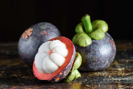 Closeup view of fresh ripe mangosteen on old wooden table. Amazing tropical fruit with sweet white...
