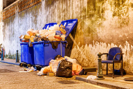Overflowed garbage bins. View of trash cans on night street.の写真素材