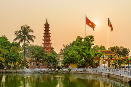 Hanoi, Vietnam - April 19, 2019: Awesome sunset view of the Tran Quoc Pagoda and West Lake. The flag of Vietnam (red flag with a gold star) and the Vietnamese Buddhist flag fluttering over the lake.のeditorial素材
