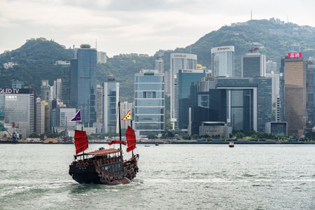 Hong Kong - October 20, 2017: Scenic Chinese wooden sailing ship with red sails crossing Victoria...