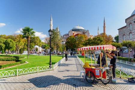 Istanbul, Turkey - September 16, 2021: Street vendor sells corn at the Sultanahmet Square. Tourists and residents rest and walk along the scenic city park. Awesome view of the Hagia Sophia.のeditorial素材