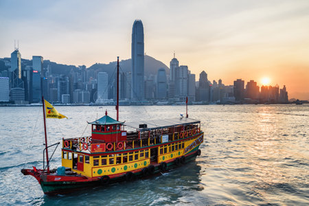Hong Kong - October 21, 2017: Tourist boat crossing Victoria Harbor at sunset. Awesome view of skyscrapers in downtown. Hong Kong Island skyline. Hong Kong is a popular tourist destination of Asia.のeditorial素材
