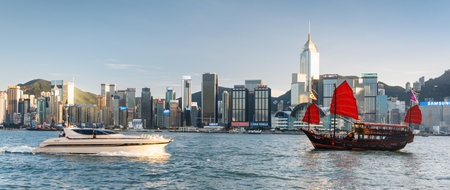 Hong Kong - November 8, 2015: Wooden tourist sailboat and modern speed-boat crossing Victoria harbor. Hong Kong is a popular tourist destination of Asia.のeditorial素材