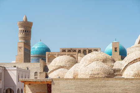 Awesome view of roof of the Trading Dome Toqi Zargaron and dome of the Mir-i-Arab Madrasa in Bukhara, Uzbekistan. The Kalan Minaret of Po-i-Kalan complex is visible on blue sky background.の写真素材