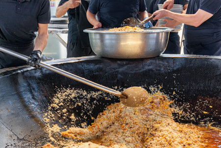 Uzbek plov (pilaf) is being prepared in giant kazan, Tashkent, Uzbekistan. The signature dish of Uzbekistan is cooked with rice, meat, carrots and onions. Pilaf is a traditional food at Central Asia.の写真素材