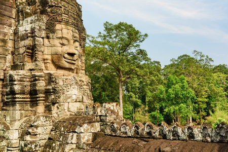 Giant stone face of ancient Bayon temple. Bayon temple nestled in Angkor Thom, Siem Reap, Cambodia. Angkor Thom is a popular tourist attraction.の写真素材