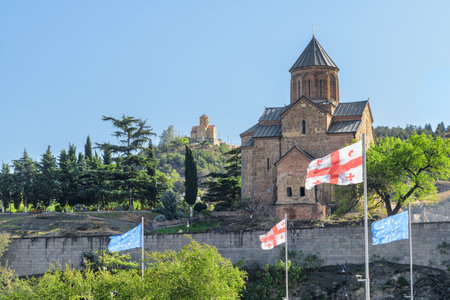 Scenic view of the Virgin Mary Assumption Church of Metekhi in Tbilisi, Georgia. The flag of Georgia and the European Flag are fluttering in wind. Georgia is a popular tourist destination.の写真素材