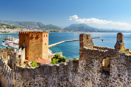 Awesome view of the Kizil Kule (Red Tower) from fortress walls of Alanya Castle in Turkey. The Mediterranean Sea is visible in background. The octagonal red brick tower is a popular tourist attractionの写真素材