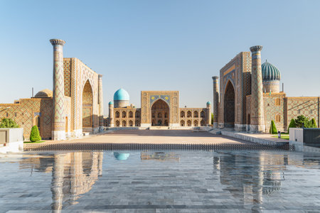 Awesome view of the Registan Square in Samarkand, Uzbekistan. The Ulugh Beg Madrasah and the Sher-Dor Madrasah reflected in wet floor. The Registan is a popular tourist attraction of Central Asia.の写真素材