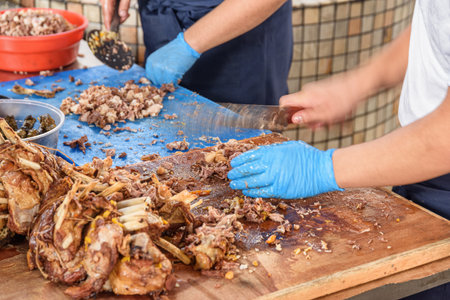 Cookers are cutting meat from plov (pilaf) for serving, Tashkent, Uzbekistan. The signature dish of Uzbekistan cooked with rice, meat, carrots and onions. Pilaf is a traditional food at Central Asia.の写真素材