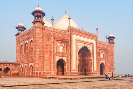 The Kau Ban Mosque of the Taj Mahal complex on blue sky background in Agra, India. Amazing red sandstone building reflected in water of pool. Wonderful Mughal architecture.の写真素材