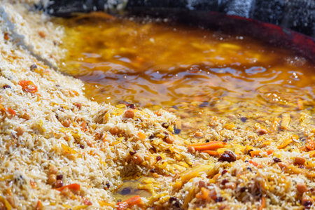 Fresh cooked wedding Uzbek plov in giant kazan, Tashkent, Uzbekistan. The signature dish of Uzbekistan is cooked with rice, meat, carrots and onions. Pilaf is a traditional food at Central Asia.の写真素材