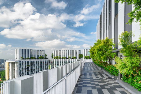 Amazing rooftop garden. Scenic outside terrace with park and beautiful city view. Modern benches under green trees along walkway. Urban eco design and mini-ecosystem. Landscaping in Singapore.のeditorial素材