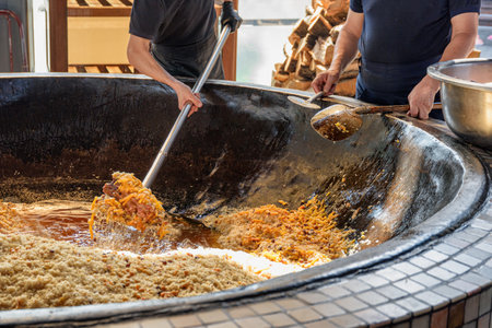 Uzbek plov (pilaf) is being prepared in giant kazan, Tashkent, Uzbekistan. The signature dish of Uzbekistan is cooked with rice, meat, carrots and onions. Pilaf is a traditional food at Central Asia.の写真素材