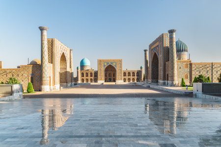 Awesome view of the Registan Square in Samarkand, Uzbekistan. The Ulugh Beg Madrasah and the Sher-Dor Madrasah reflected in wet floor. The Registan is a popular tourist attraction of Central Asia.の写真素材