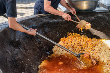 Uzbek plov (pilaf) is being prepared in giant kazan, Tashkent, Uzbekistan. The signature dish of Uzbekistan is cooked with rice, meat, carrots and onions. Pilaf is a traditional food at Central Asia.の写真素材