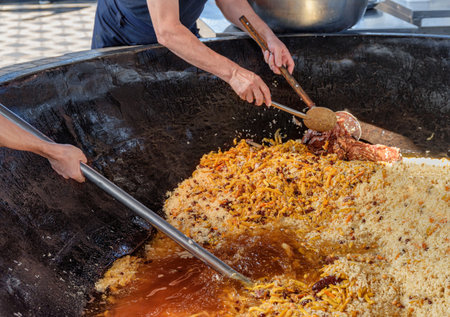 Uzbek plov (pilaf) is being prepared in giant kazan, Tashkent, Uzbekistan. The signature dish of Uzbekistan is cooked with rice, meat, carrots and onions. Pilaf is a traditional food at Central Asia.の写真素材