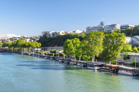 Scenic view of the Kura (Mtkvari) River in Old Town of Tbilisi, Georgia. The Ceremonial Palace of Georgia (formerly Presidential Palace) is visible on blue sky background.の写真素材