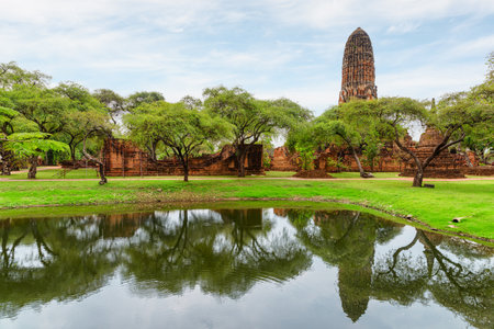 Awesome tower (prang) of Wat Phra Ram is reflected in pond at Ayutthaya, Thailand. Scenic ruins of the Buddhist temple in the ancient city of the Ayutthaya Kingdom (Siam).の写真素材