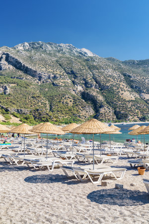 Scenic view of beach umbrellas and sun loungers on Oludeniz Beach in Turkey. Wonderful mountains are visible in background. Oludeniz is a popular tourist attraction in Turkey.の写真素材