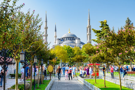 Awesome view of the Sultan Ahmed Mosque (the Blue Mosque) among green gardens. Tourists and residents rest and walk along scenic city park.の写真素材