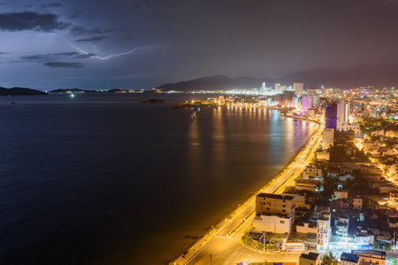 Dramatic dark stormy sky and lightning over Nha Trang Bay of South China Sea in Khanh Hoa province at night in Vietnam. Nha Trang city is a popular tourist destination of Asia.の写真素材