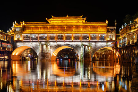 Colorful night view of the Hong Bridge (Rainbow Bridge) over the Tuojiang River (Tuo Jiang River) in Phoenix Ancient Town (Fenghuang County), China. Fenghuang is a popular tourist destination of Asia.の写真素材